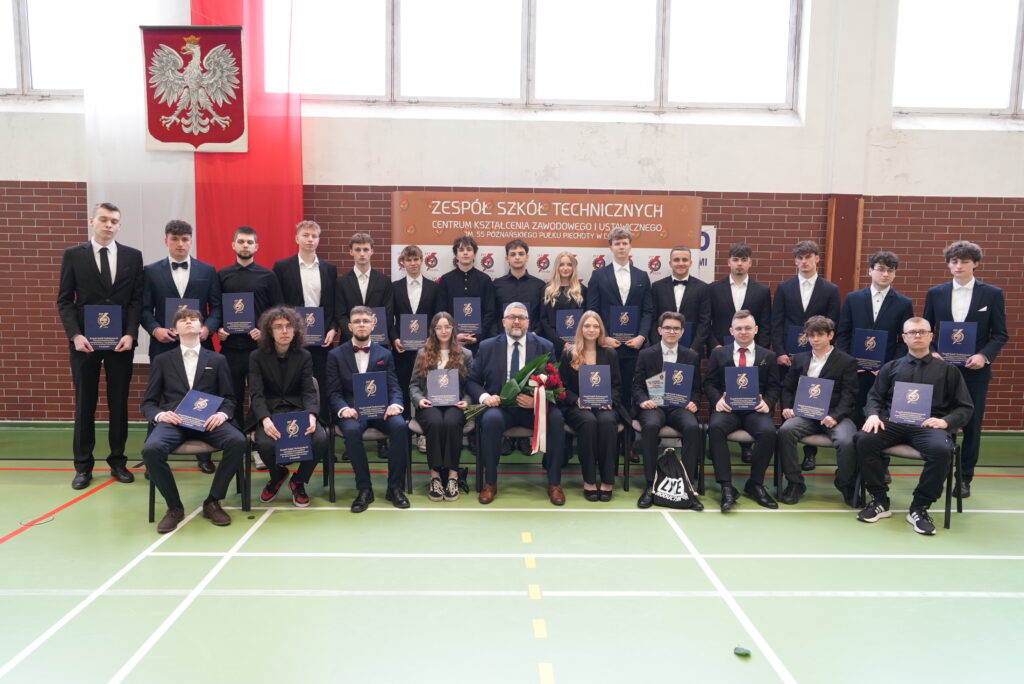 Group of Students in Suits Posing for a Formal Graduation Photo in a School Gym Holding Blue Diplomas 9 Września 2025 Dsc00473