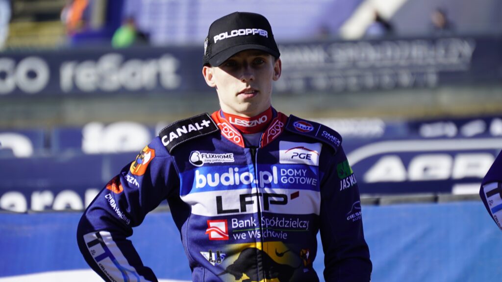 Portrait of a Motorcycle Racer in a Navy Blue Racing Suit with Sponsor Patches and a Black Cap at a Race Track Finish Area 9 Września 2025  ml 3429