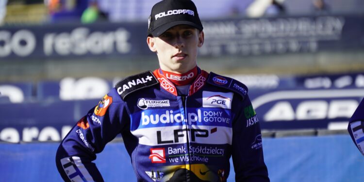 ML3429 Portrait of a Motorcycle Racer in a Navy Blue Racing Suit with Sponsor Patches and a Black Cap at a Race Track Finish Area 22 Maja 2026 ml 3429