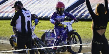 Motocross Race Scene with a Rider in Purple Gear and Red Helmet on a Blue Bike Paused Near the Track While Two People Stand Nearby 15 Czerwca 2020
