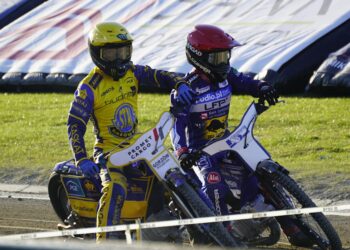 Two Speedway Riders in Yellow and Purple Racing Suits Lean into a Turn on a Dirt Track with Grass in the Background 28 Czerwca 2020 
