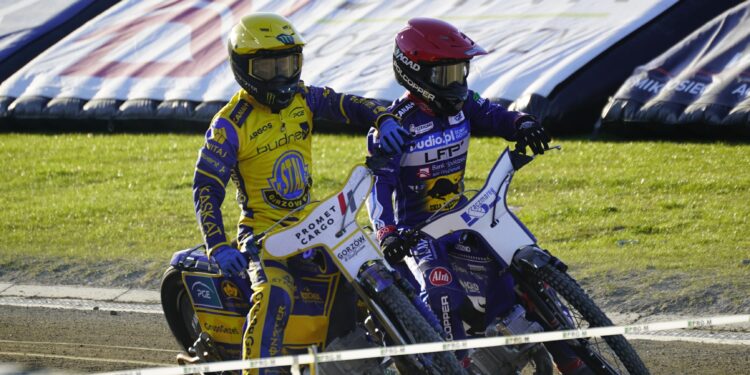 Two Speedway Riders in Yellow and Purple Racing Suits Lean into a Turn on a Dirt Track with Grass in the Background 26 Kwietnia 2026 