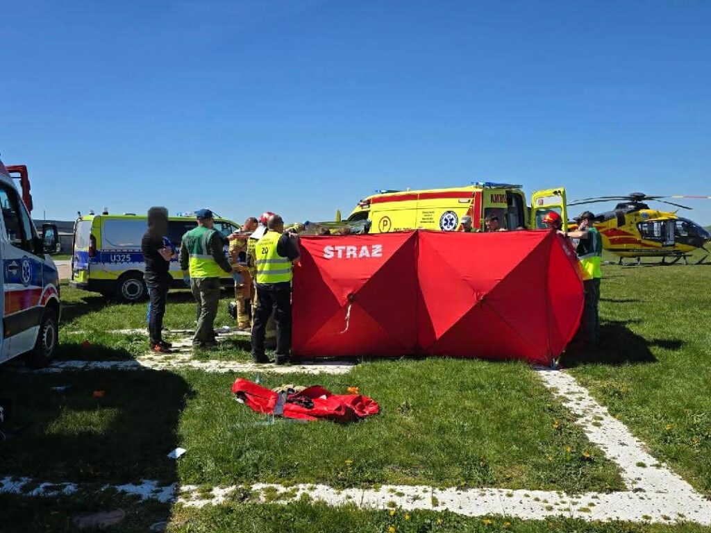Emergency Responders Set Up a Bright Red Tent Labeled straŻ on a Grassy Field with Ambulances and a Yellow Helicopter in the Background 9 Września 2025 