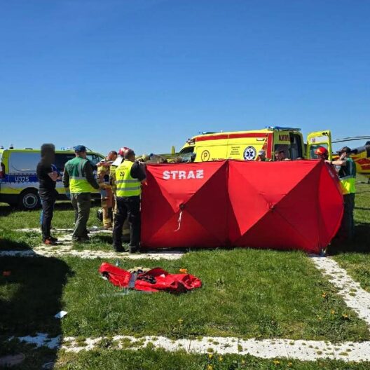 Emergency Responders Set Up a Bright Red Tent Labeled straŻ on a Grassy Field with Ambulances and a Yellow Helicopter in the Background 9 Września 2025 