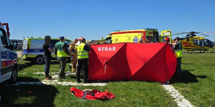 Emergency Responders Set Up a Bright Red Tent Labeled straŻ on a Grassy Field with Ambulances and a Yellow Helicopter in the Background 1 Maja 2026 