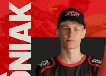 Portrait of a Young Athlete Wearing a Black Cap and Red and black Jersey Facing the Camera Against a Bold Red Backdrop with Large White Text on the Left 13 Września 2020 