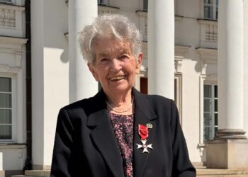 Smiling Elderly Woman in a Black Blazer with a Red Ribbon Medal Standing Outside a White Columned Building 11 Czerwca 2019