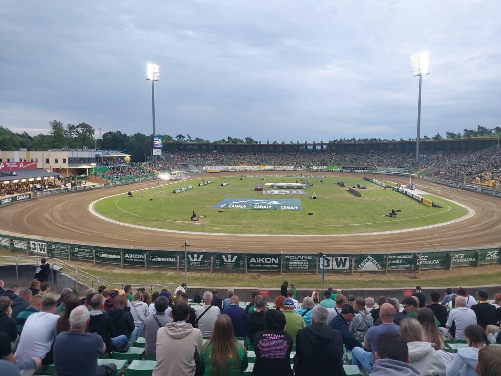 Crowded Outdoor Stadium with a Dirt Race Track Curved Turns and Tall Floodlights Overhead 9 Września 2025
