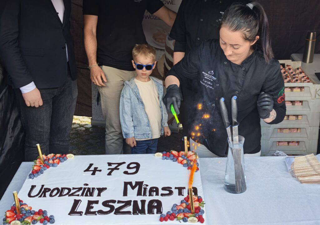 Child Wearing Blue Sunglasses Watches As a Chef in Black Oversees a Flaming Dessert Cake Decorated with Strawberries and Blueberries at a City Birthday Event 9 Września 2025 