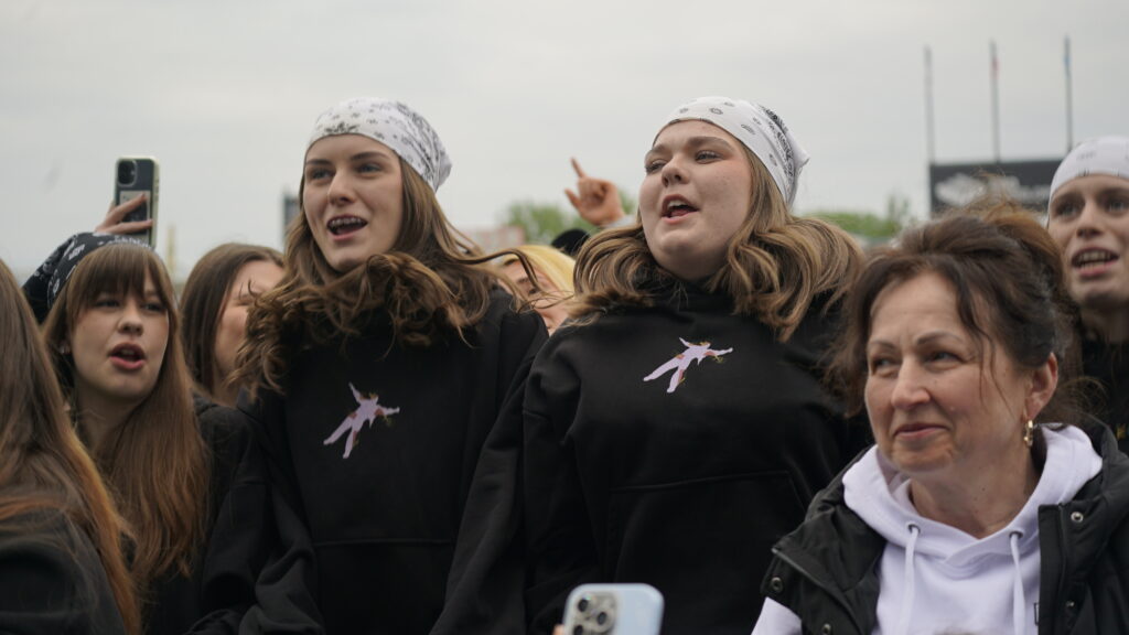 Group of Young People Cheering at an Outdoor Event Two Central Girls Wear White Bandanas and Black Hoodies 9 Września 2025