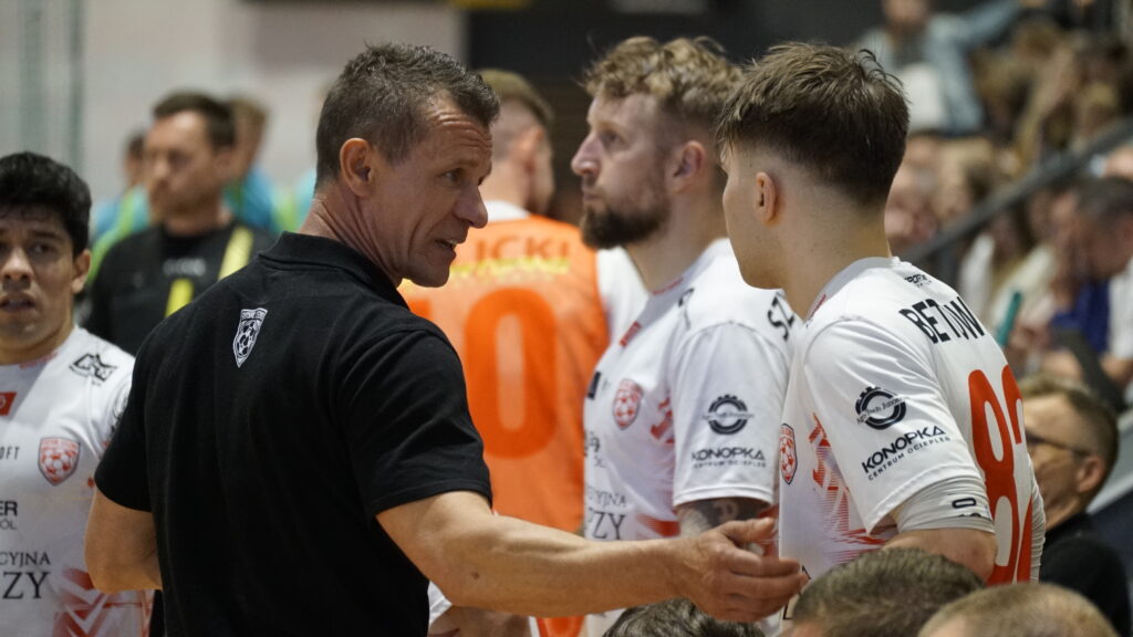 Coach in Black Shirt Shaking Hands with Athletes Wearing White Jerseys After a Game in a Crowded Indoor Venue 9 Września 2025