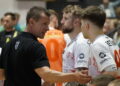 Coach in Black Shirt Shaking Hands with Athletes Wearing White Jerseys After a Game in a Crowded Indoor Venue 16 Czerwca 2020