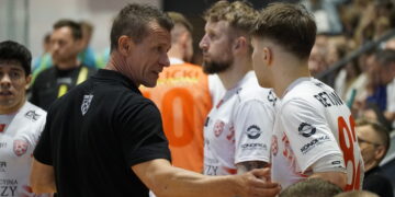 Coach in Black Shirt Shaking Hands with Athletes Wearing White Jerseys After a Game in a Crowded Indoor Venue 14 Czerwca 2020