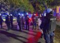 Line of Riot Police in Body Armor and Helmets with Shields Standing on a City Street at Night Blue and Red Flashing Patrol Lights in the Background 16 Czerwca 2020