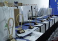 Row of Award Trophies and Gift Bags Lined Up on a Blue Table at an Awards Ceremony with a Blue Backdrop in the Background 15 Czerwca 2020  ml 5750