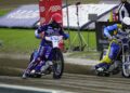 Three Speedway Riders in Blue and Yellow Suits Race on a Muddy Track Kicking Up Dirt As They Round a Bend with Banners in the Background 15 Czerwca 2020